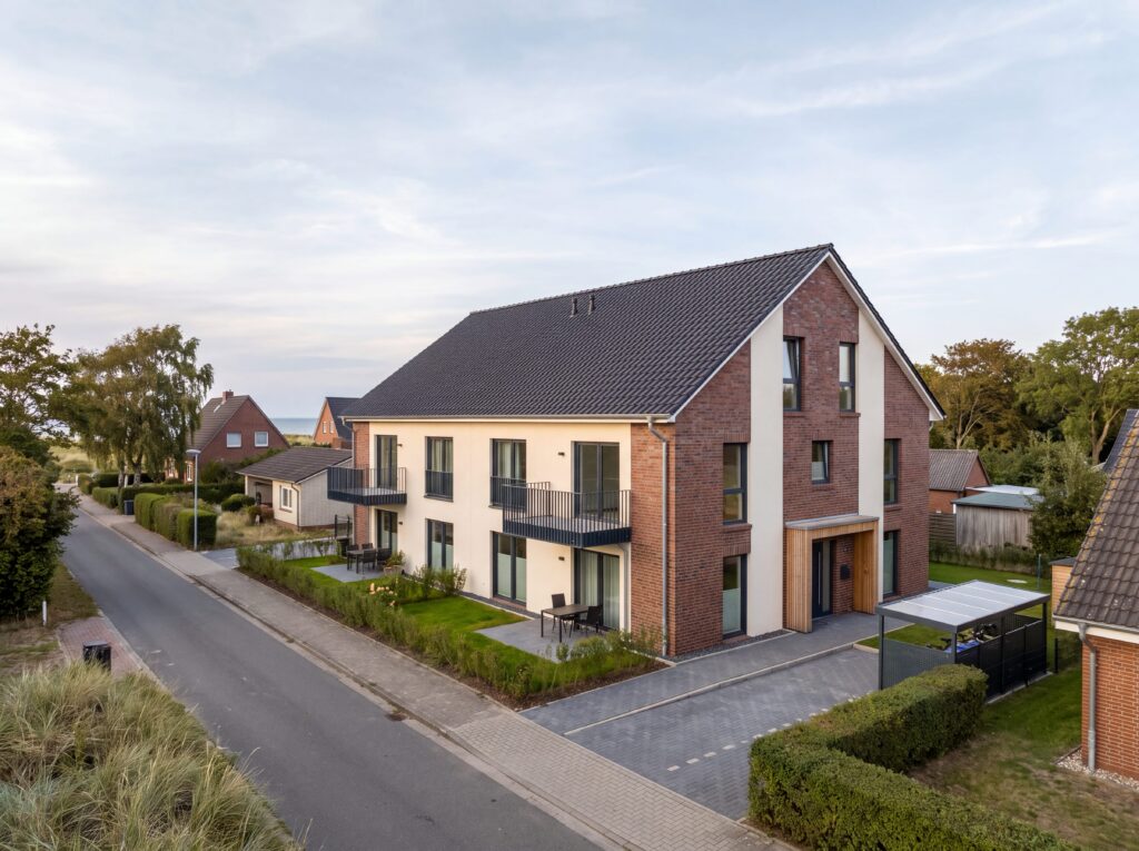 Modernes Ferienwohngebäude mit Klinkerfassade, Balkonen und Ostsee im Hintergrund